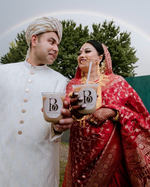Bride and groom toasting with Barista Bhai cups under a rainbow